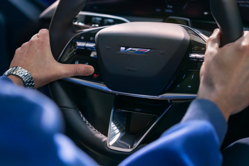 Close-up of a Man About to Press the V-Button on the 2026 OPTIQ-V Steering Wheel | Moses Cadillac of Huntington in Huntington WV